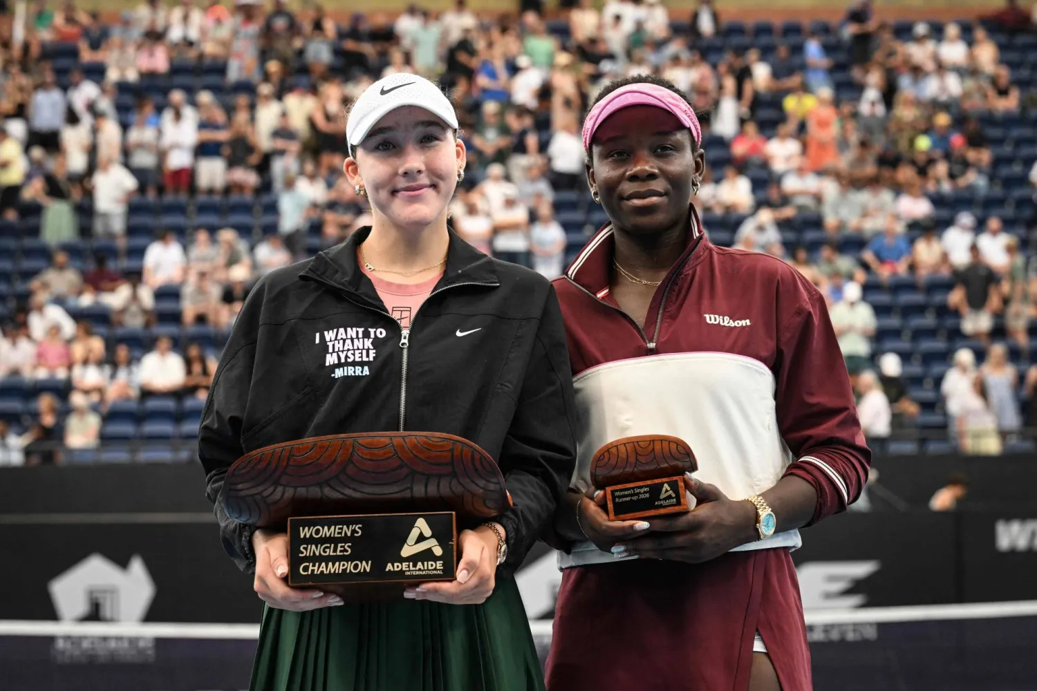 الروسية ميرا أندرييفا (يسار) تحتفل بكأس أديلايد إلى جوار الكندية فيكتوريا مبوكو (أ.ف.ب)