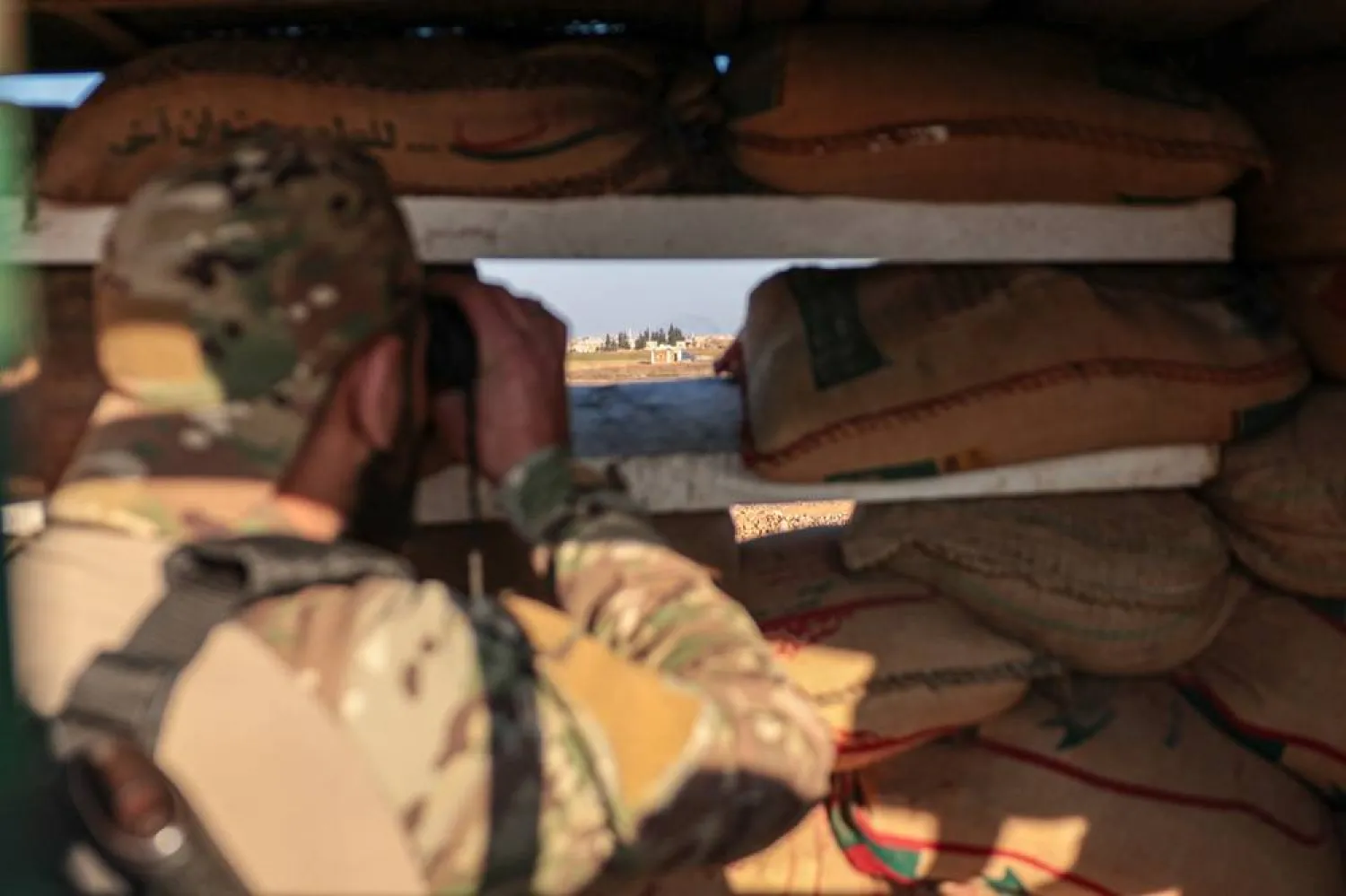 A member of the Syrian army monitors the frontline from a fortified military post in the Deir Hafer area, eastern Aleppo countryside, northern Syria, 16 January 2026. (EPA)