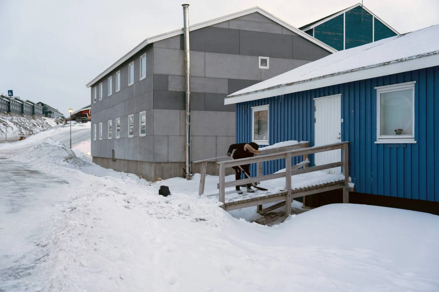 A woman uses a shovel to clear a footpath from now and ice on January 16, 2026 in Nuuk, Greenland. (AFP)