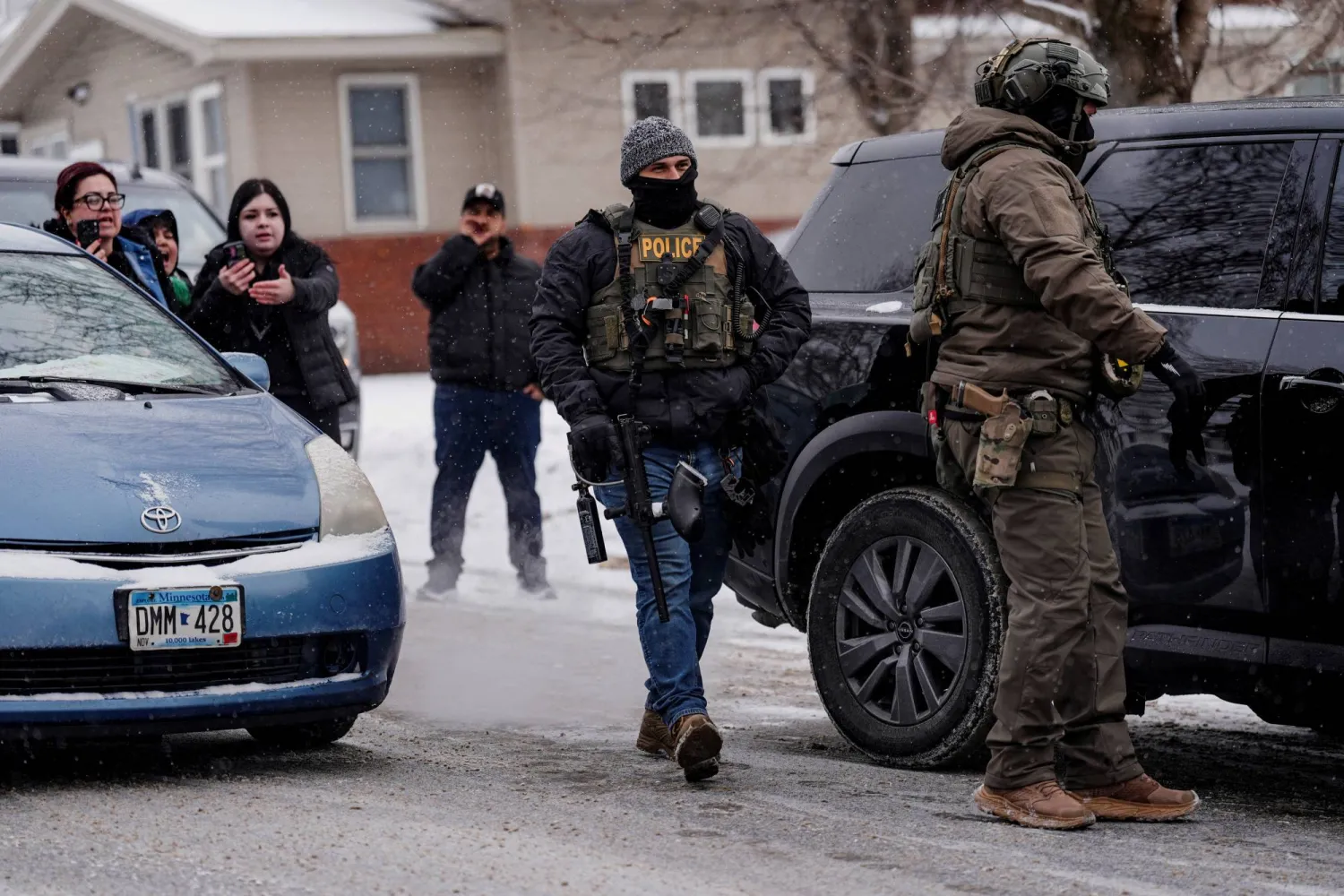 عناصر من هيئة الهجرة والجمارك الأميركية وضباط شرطة خلال تنفيذ غارات للبحث عن مهاجرين في ولاية مينيسوتا (رويترز) 