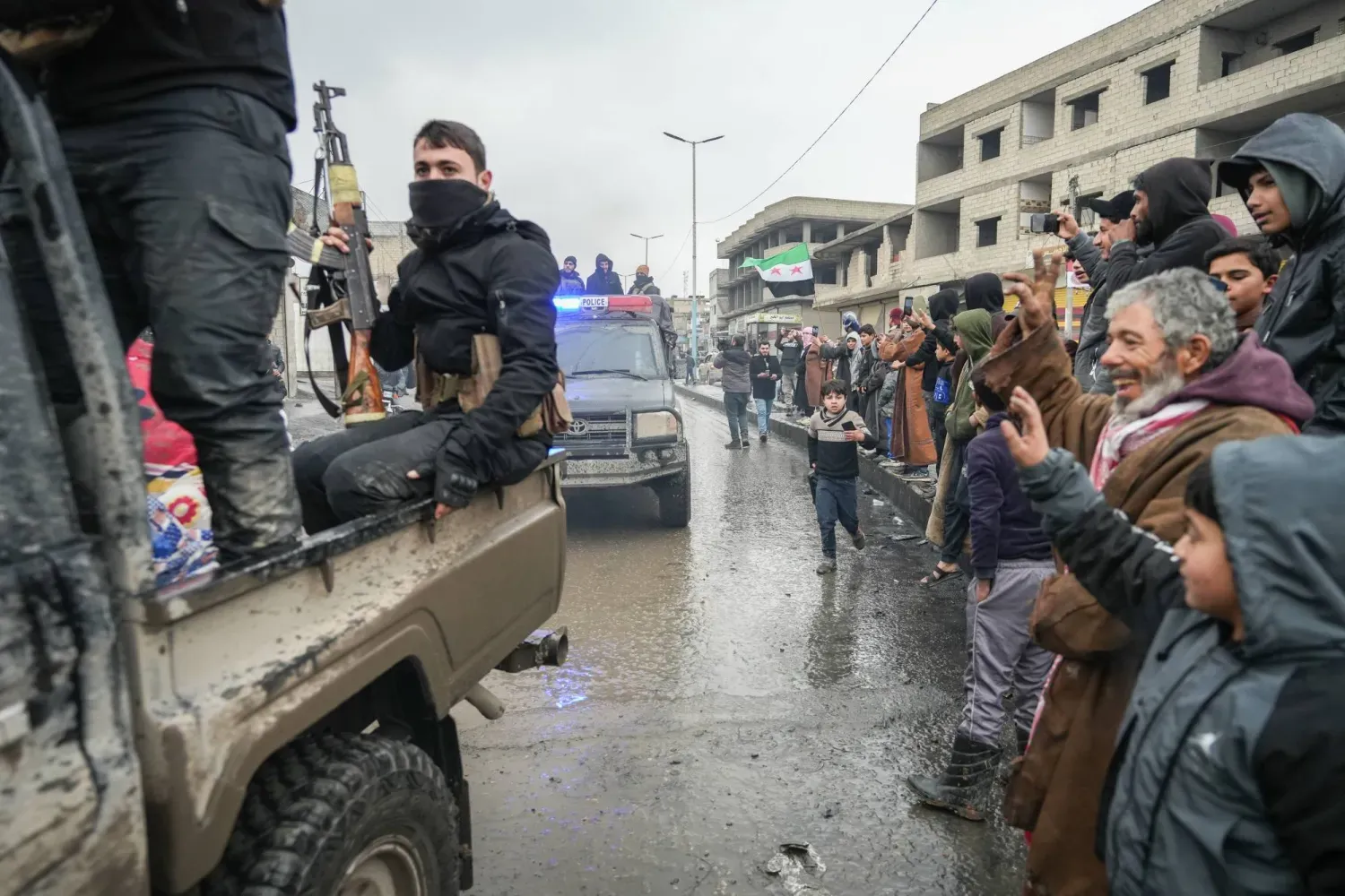 Yol kenarında sıralanarak, Rakka’daki Tabka ilçesine giren Suriye güvenlik güçlerine el sallayan Suriyeliler (EPA)