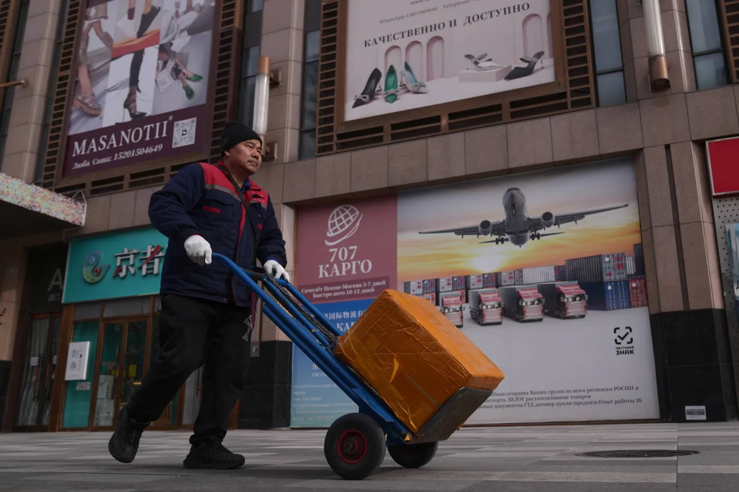 A deliver worker transfers the merchandise outside the Ritan International Trade Center in Beijing, Monday, Jan. 19, 2026. (AP Photo/Andy Wong)
