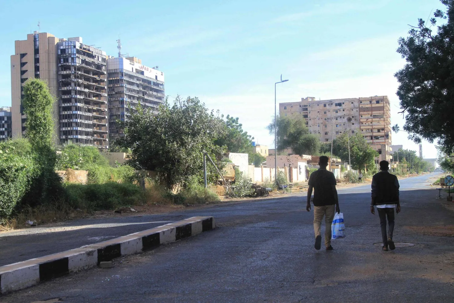 Men walk along a street past destroyed high-rise building, as efforts to restore the city's infrastructure resumes after nearly three years of devastation caused by war, in the Sudanese capital Khartoum on January 17, 2025. (AFP)