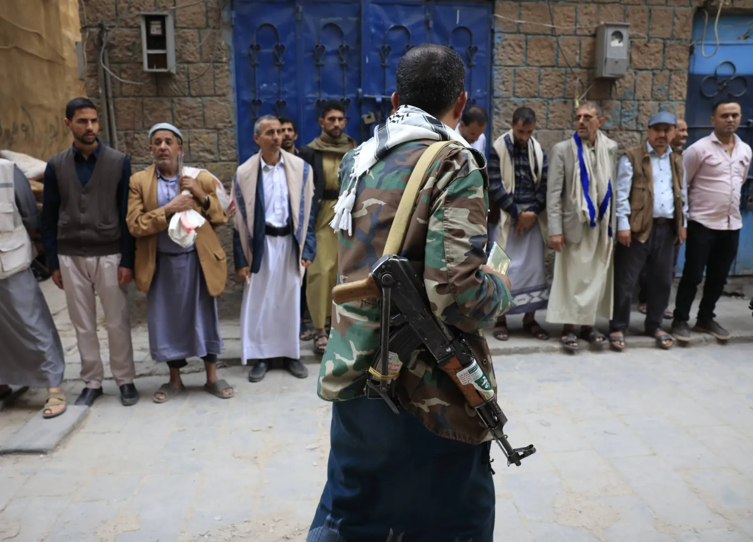 مسلّح حوثي يمر أمام تجمع للسكان بأحد أحياء صنعاء (إ.ب.أ)