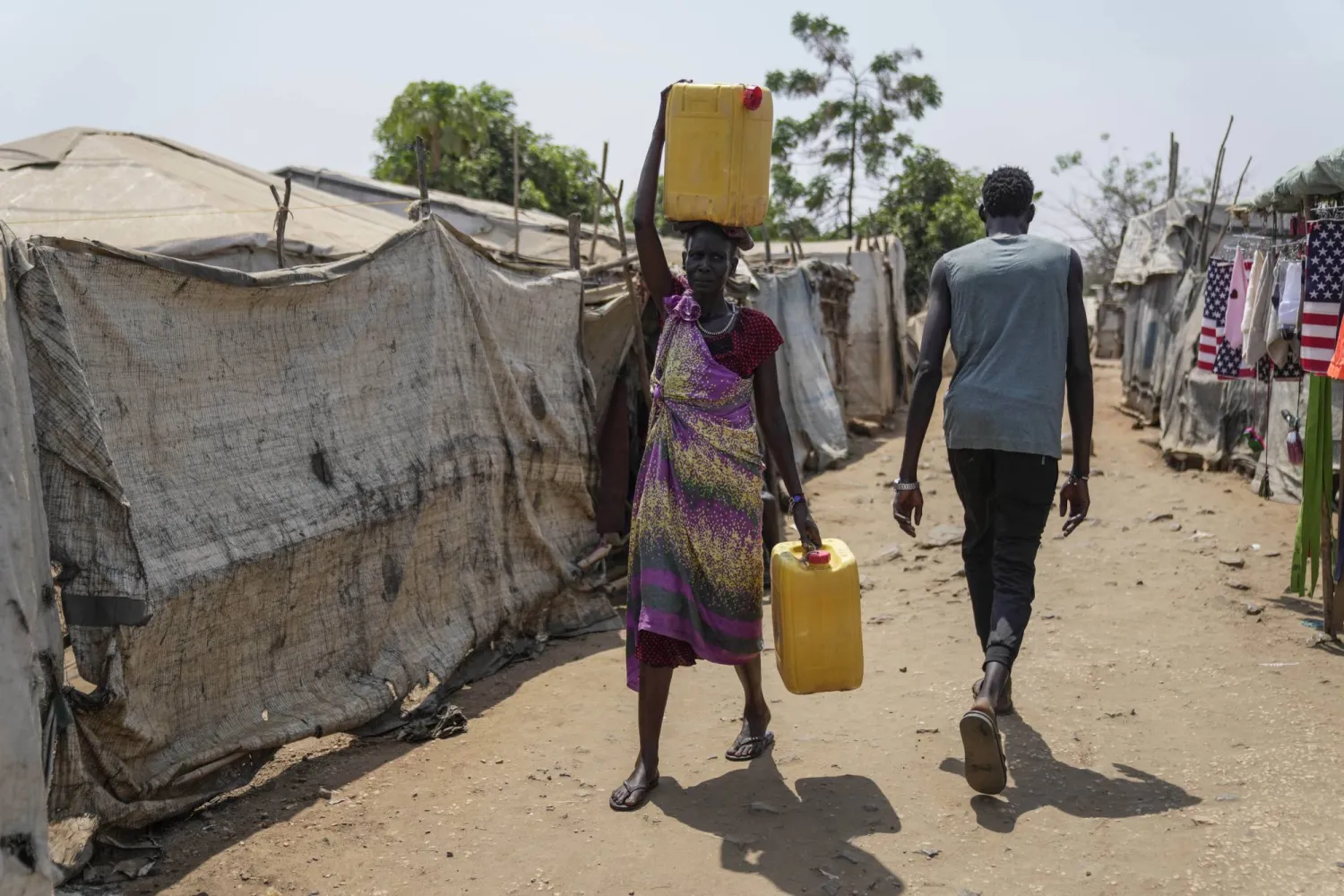 نازحة تحمل الماء على رأسها في مخيم جوبا للنازحين جنوب السودان (أ.ب)