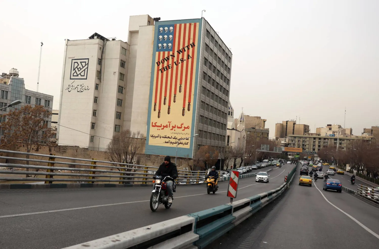 Iranians drive near an anti-US mural in street in Tehran, Iran, 19 January 2026. (EPA)