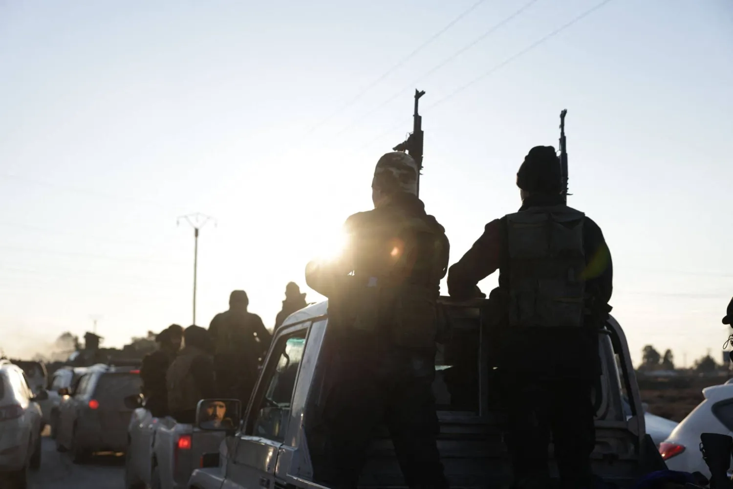 Syrian government forces brandish their weapons as they take possession of the SDF military base as they enter the city of Raqqa on January 19, 2026. (AFP)
