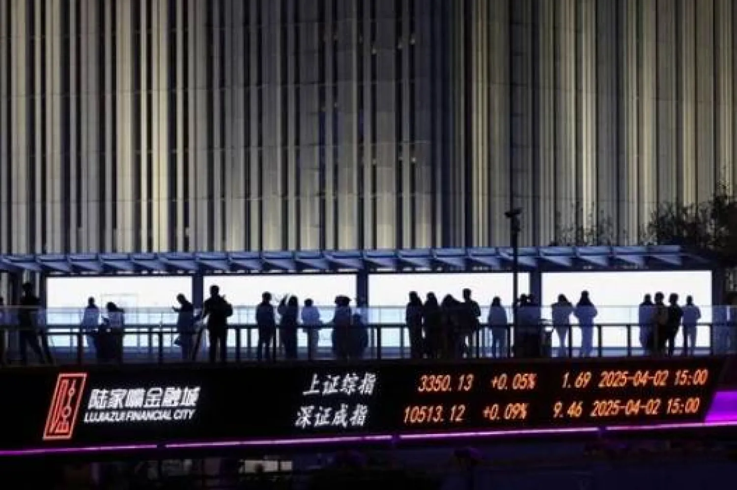 لوحة إلكترونية تعرض مؤشرات بورصتي شنغهاي وشنتشن بينما يمشي أشخاص على جسر للمشاة في منطقة لوجيازو المالية في شنغهاي (رويترز)