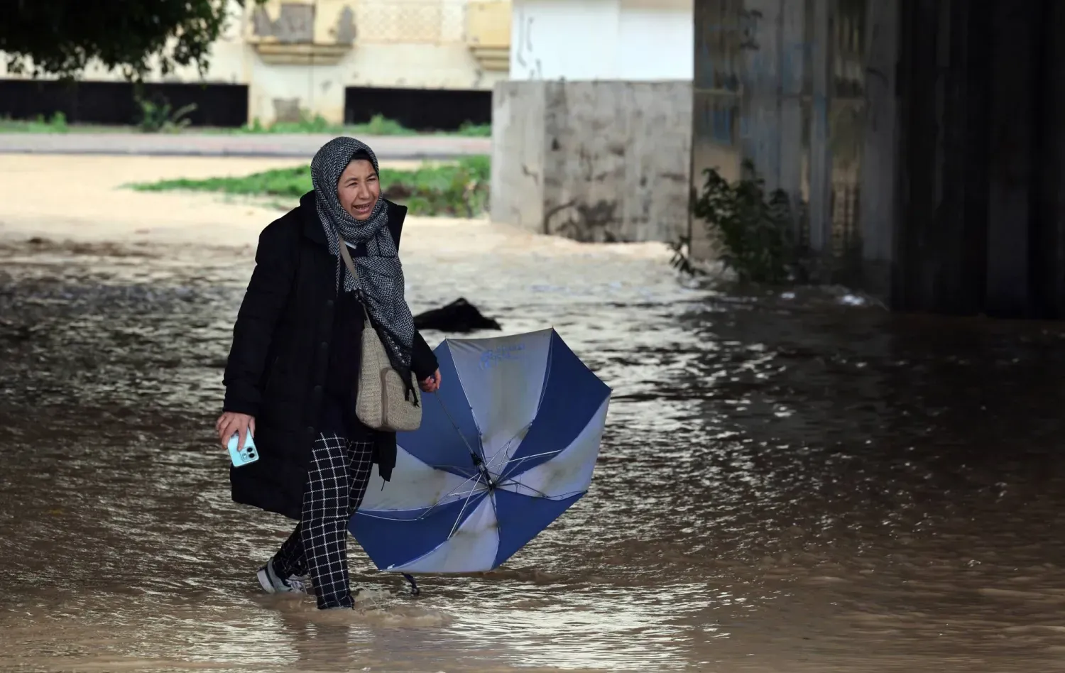 Yağmur sularında yürümeye çalışan bir kadın (EPA)