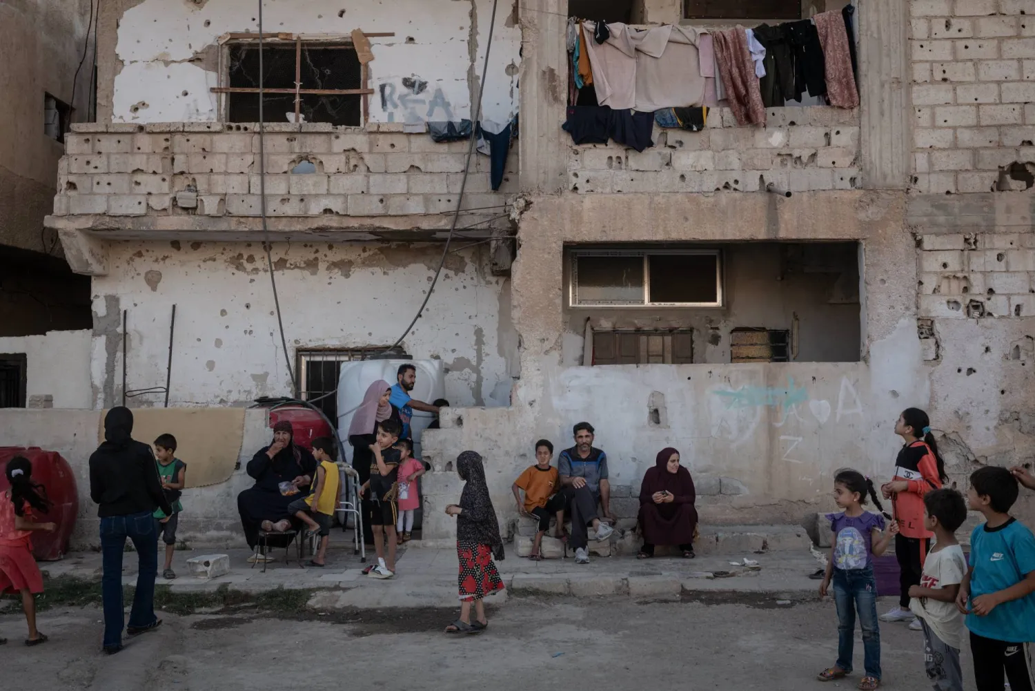 عائلة أمام أنقاض منزلها في مدينة درعا جنوب غربي سوريا مهْد الانتفاضة السورية عام (نيويورك تايمز)