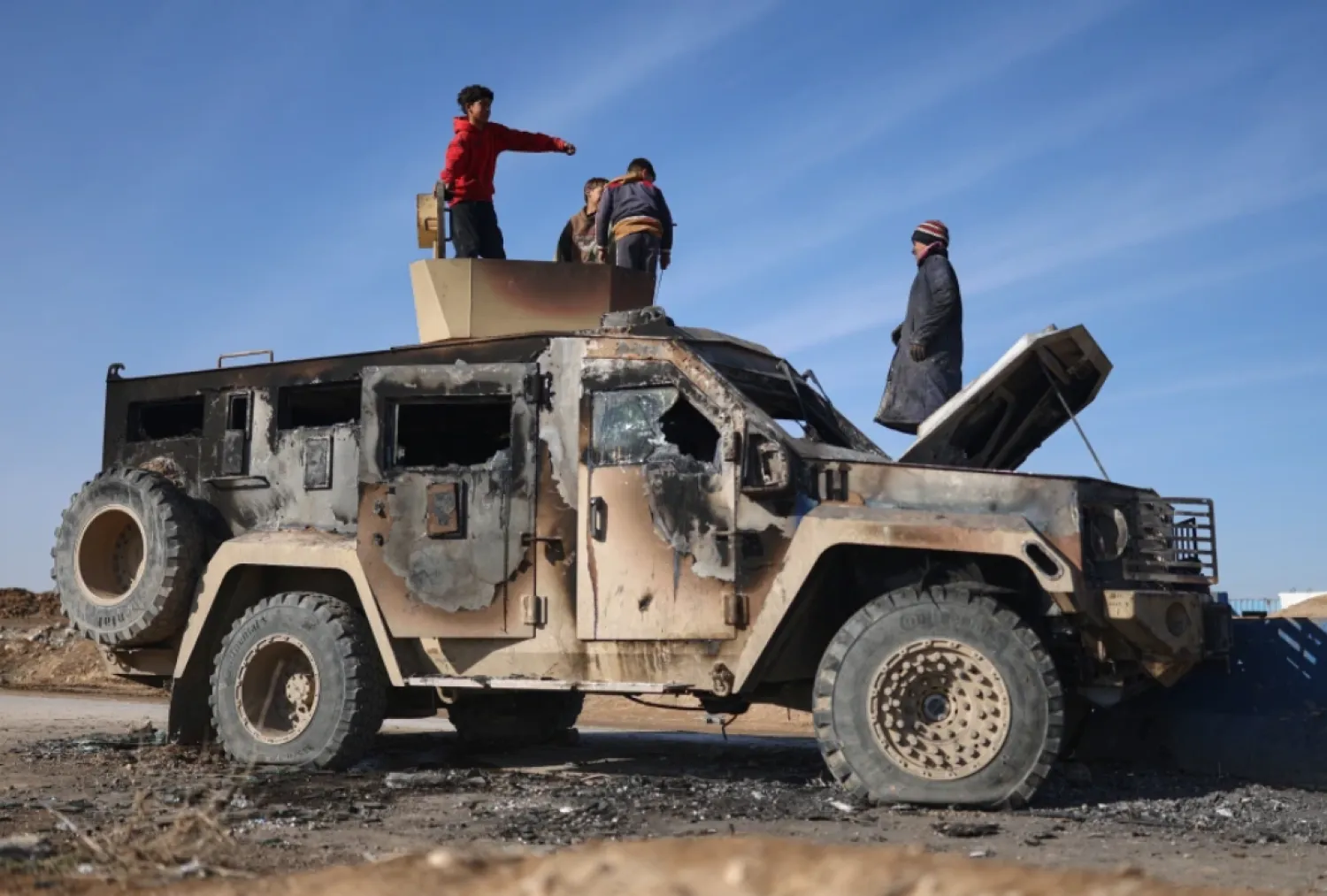 Local youth play atop of a damaged armored vehicle belonging to the Syrian Democratic Forces (SDF) at the site of clashes with Syrian government forces in the village of al-Hol in northeastern Syria’s Hasakeh province, Syria, Wednesday, Jan. 21, 2026. (AP Photo/Ghaith Alsayed)


