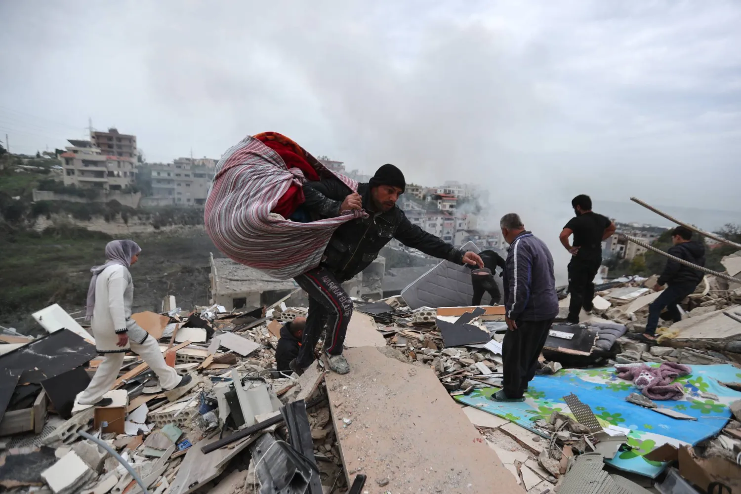 مواطنون يجمعون ما تبقّى من أغراضهم على أثر استهداف المبنى الذي يسكنون فيها ببلدة قناريت بجنوب لبنان مساء الأربعاء (أ.ب)