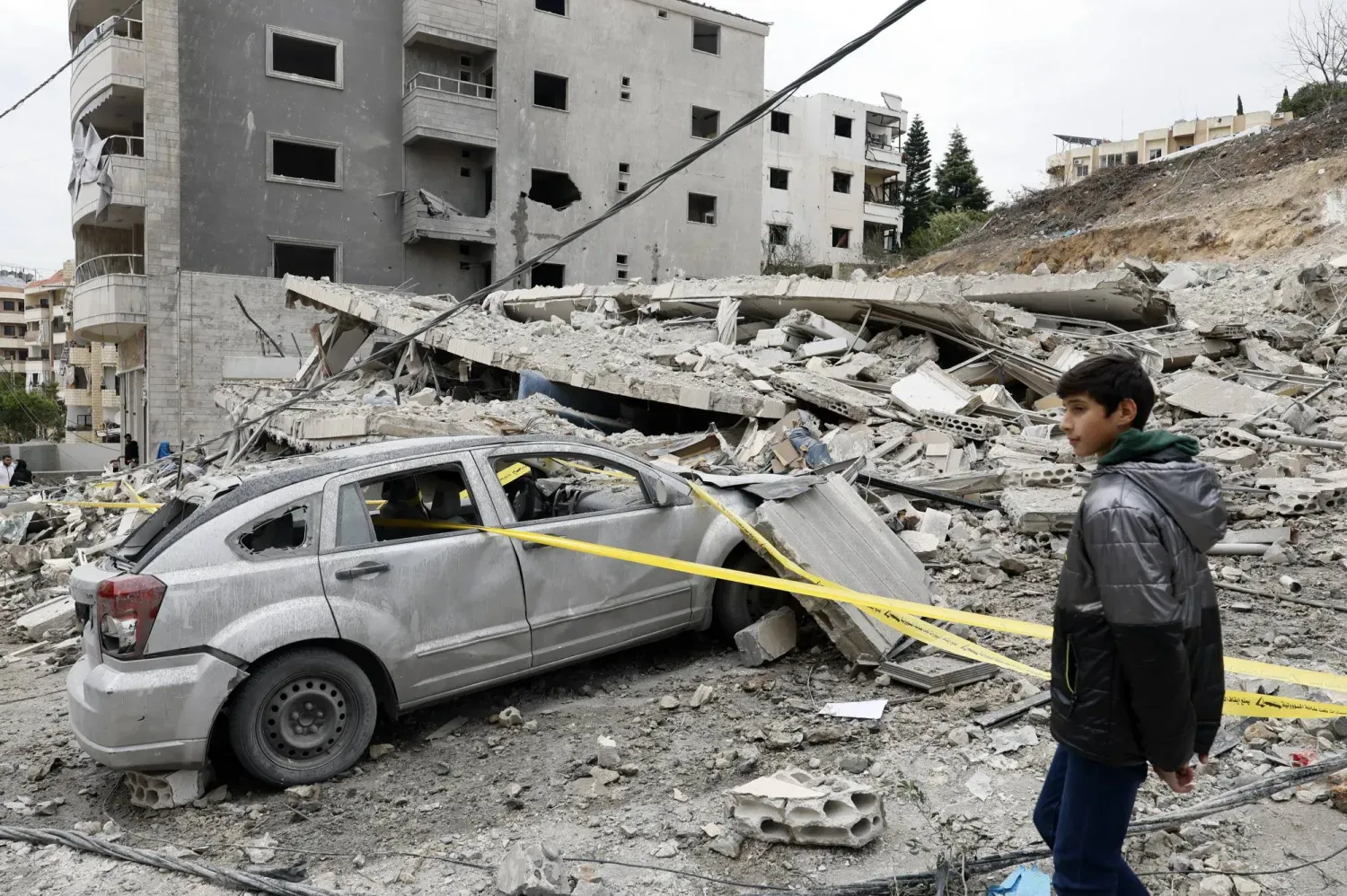 Lübnan'ın güneyindeki Kanarit kasabasına çarşamba günü İsrail'in düzenlediği hava saldırısında yıkılan bir binanın önündeki çocuk (EPA)
