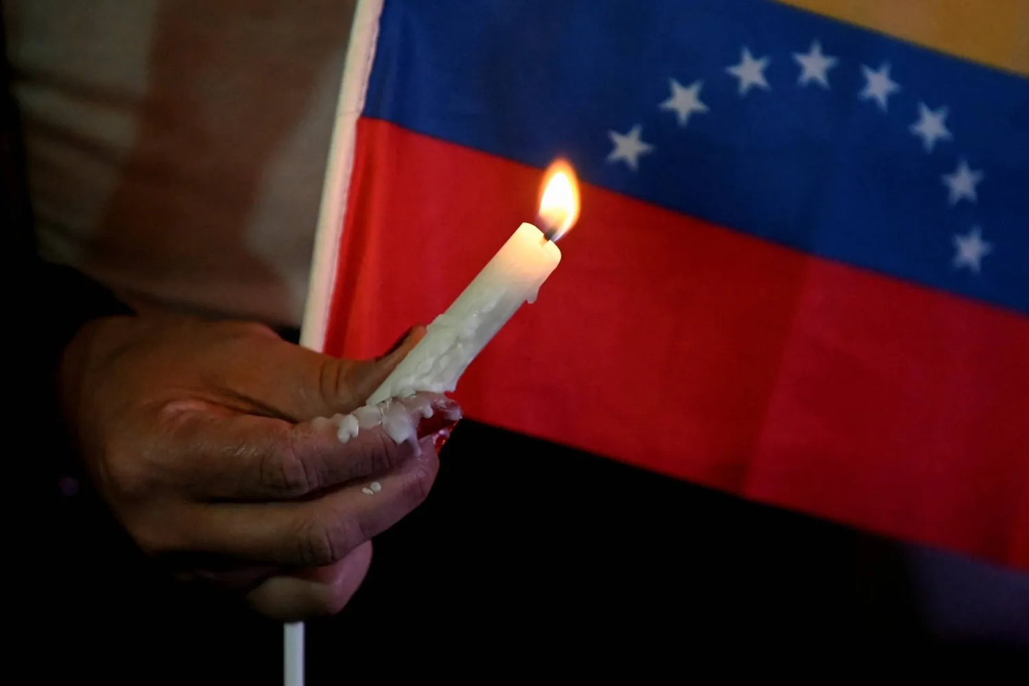 A woman holds a candle next to a Venezuelan flag during a vigil to honor those killed on January 3 during the US operation to capture Venezuela's President Nicolas Maduro and his wife Cilia Flores, at Bolivar Square in Caracas, Venezuela, January 22, 2026. (Reuters)
