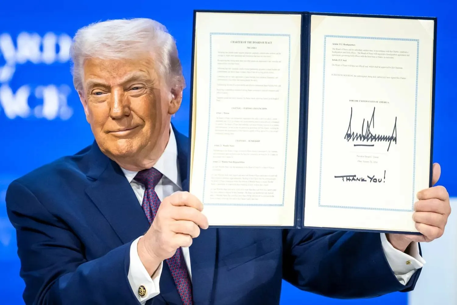 President Donald Trump, center, holds up a signed Board of Peace charter during the Annual Meeting of the World Economic Forum in Davos, Switzerland, Thursday, Jan. 22, 2026. (AP) 
