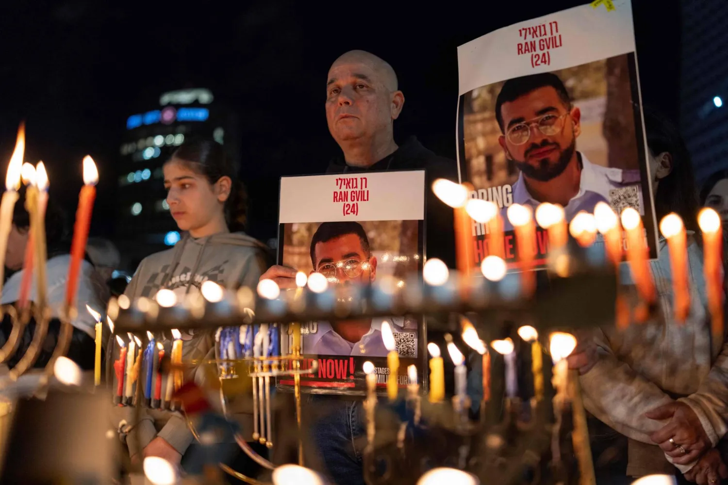 Israelis light the 8th candle of Hannukah in Hostage Square holding placards bearing the face of Ran Gvili in Tel Aviv on December 21, 2025, as they call for the return of his remains. (AFP)