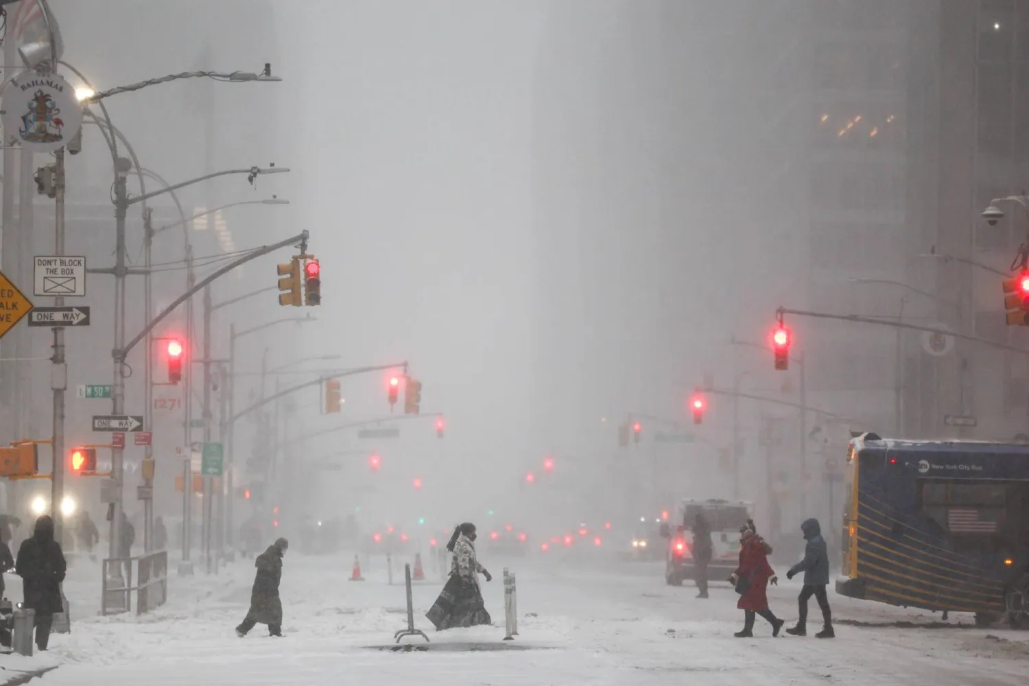 People walk across Sixth Avenue as snow falls in the Manhattan borough of New York City on January 25, 2026. (AFP)