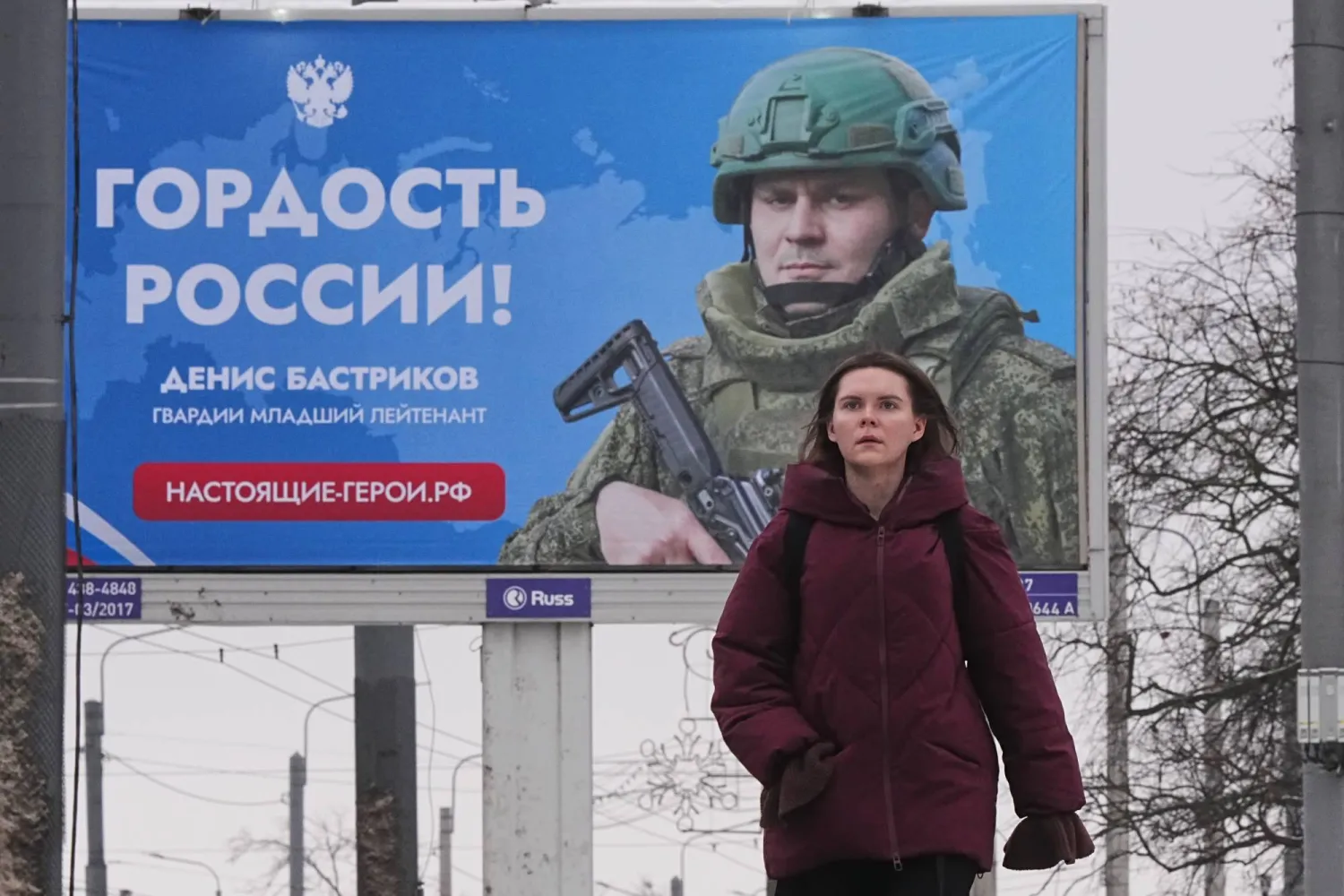 امرأة تمر أمام لوحة إعلانية تعرض جندياً روسياً مشاركاً في العمليات العسكرية بأوكرانيا مع عبارة مشفرة تقول «فخر روسيا» بسانت بطرسبرغ 20 يناير 2026 (أ.ب)