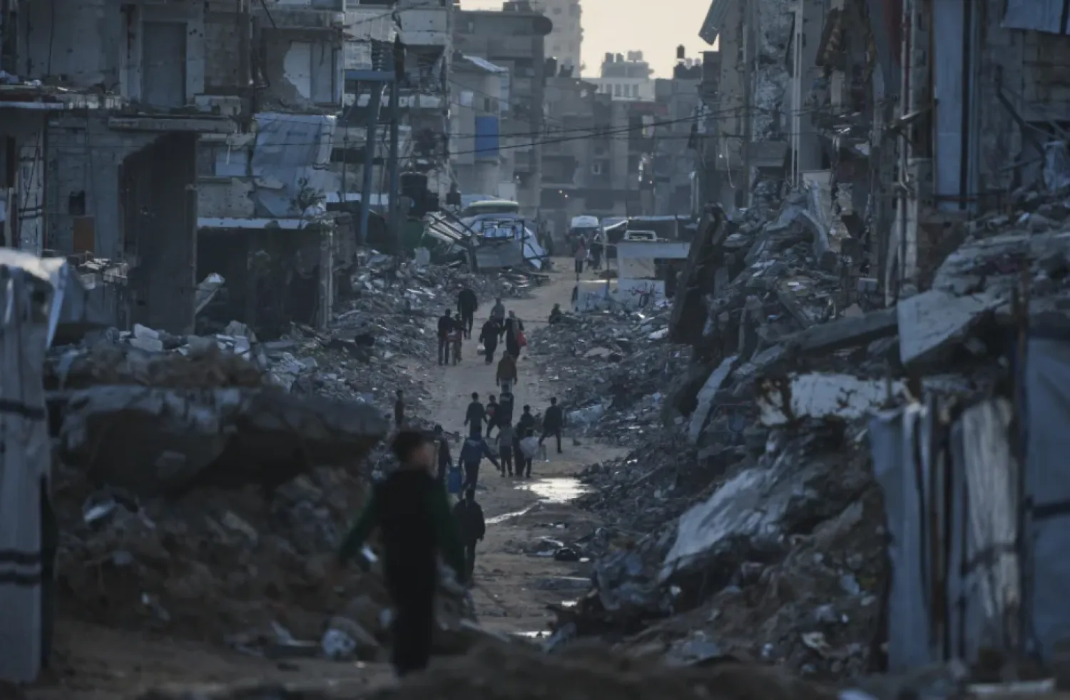 Palestinians walk amid buildings destroyed by Israeli air and ground operations in Gaza City Thursday, Jan. 15, 2026. (AP Photo/Jehad Alshrafi)

