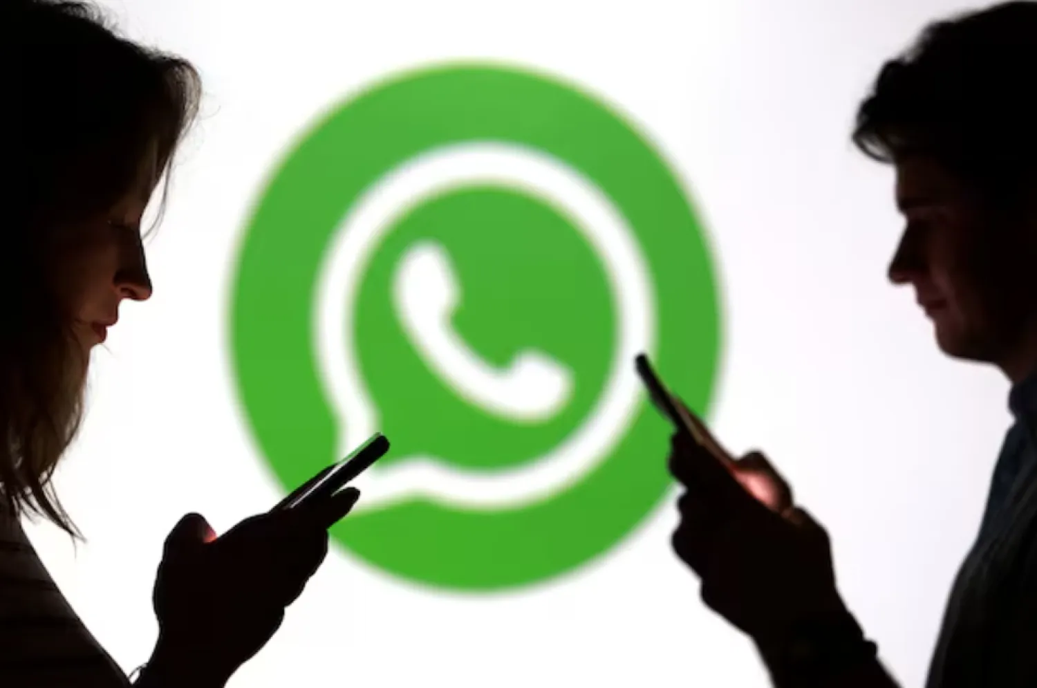 Teenagers pose for a photo while holding smartphones in front of a Whatsapp logo in this illustration taken September 11, 2025. REUTERS/Dado Ruvic/Illustration