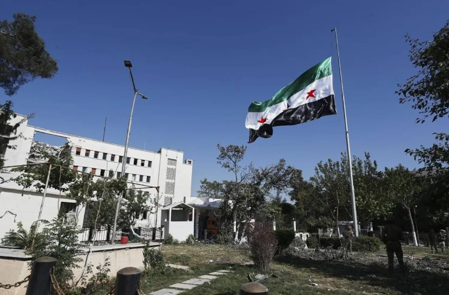 Syrian soldiers raise the Syrian national flag in front of the Syrian Defense Ministry building, which was heavily damaged by Israeli airstrikes last Wednesday, in Damascus, Syria, Saturday, July 19, 2025. (AP) 

