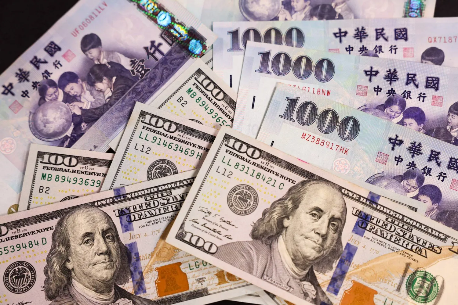أوراق نقدية من فئة 100 دولار أميركي و1000 دولار تايواني (أ.ف.ب)