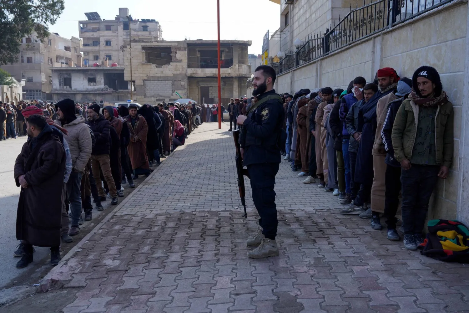 أفراد من قوات سوريا الديمقراطية (قسد) التي يقودها الأكراد يصطفون لتسوية أوضاعهم مع الحكومة السورية في الرقة (رويترز)