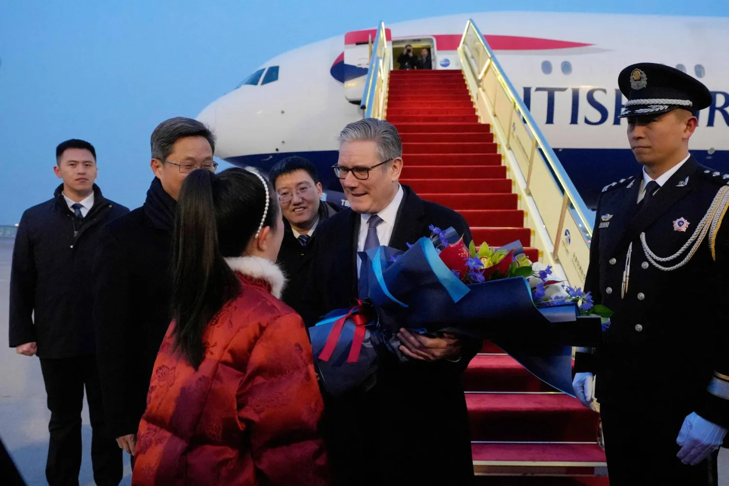 Britain's Prime Minister Keir Starmer receives a bouquet of flowers upon his arrival at an airport in Beijing on January 28, 2026. (AFP)