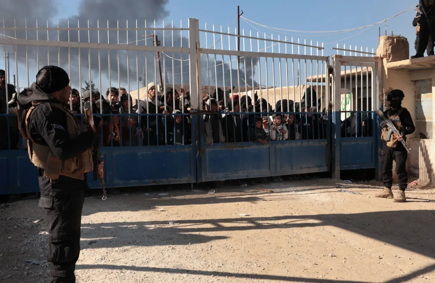 Suriye'nin kuzeydoğusunda DEAŞ üyelerinin ailelerinin kaldığı el-Hol Kampı’nın kapısının önünde duran Suriye güvenlik güçleri (EPA)