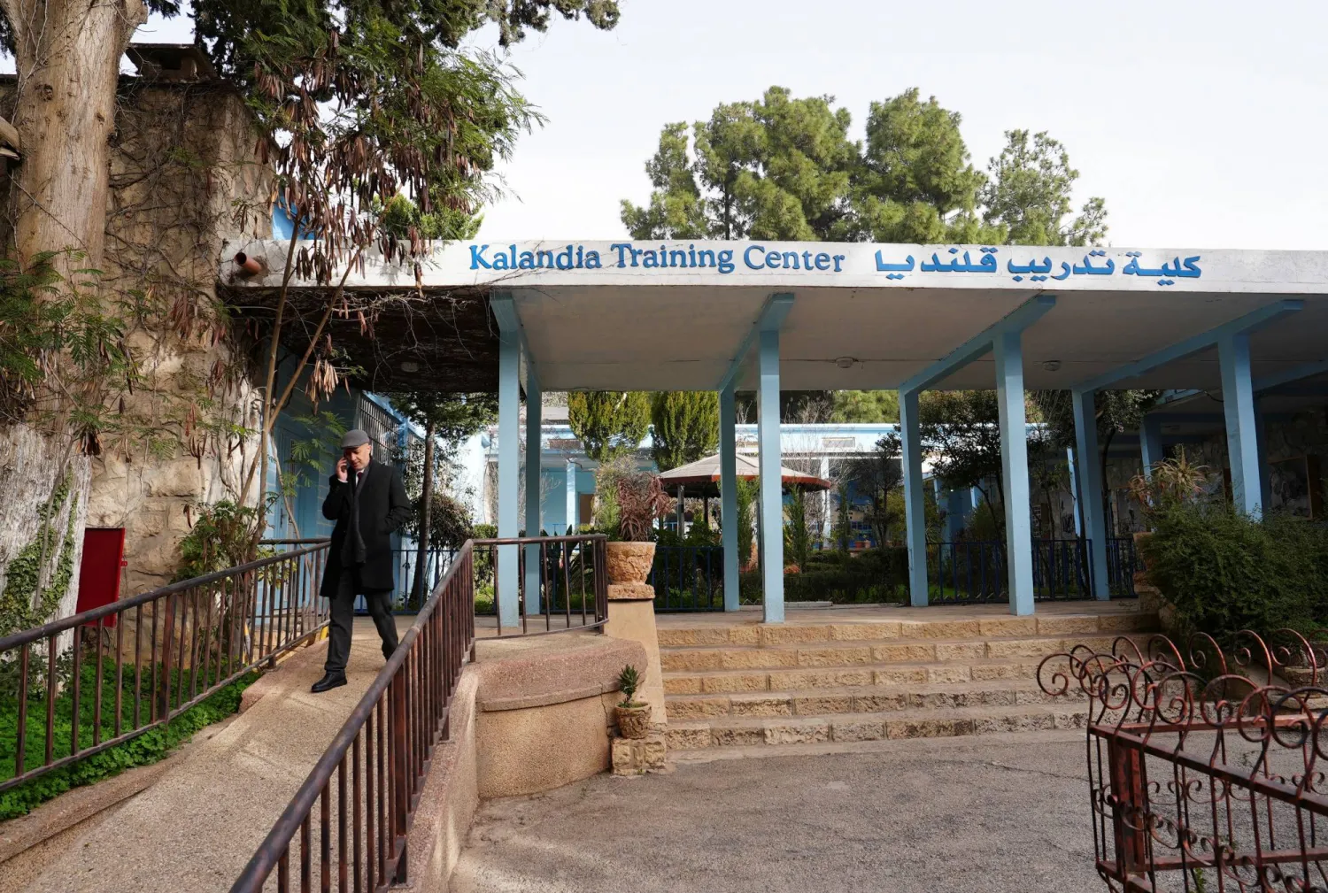 بهاء عوض مدير مركز تدريب «الأونروا» في قلنديا يتحدث عبر الهاتف أمام المركز بعد أن أفاد الموظفون بأن إسرائيل قطعت التيار الكهربائي عن المنشأة بالقرب من رام الله في الضفة (رويترز)