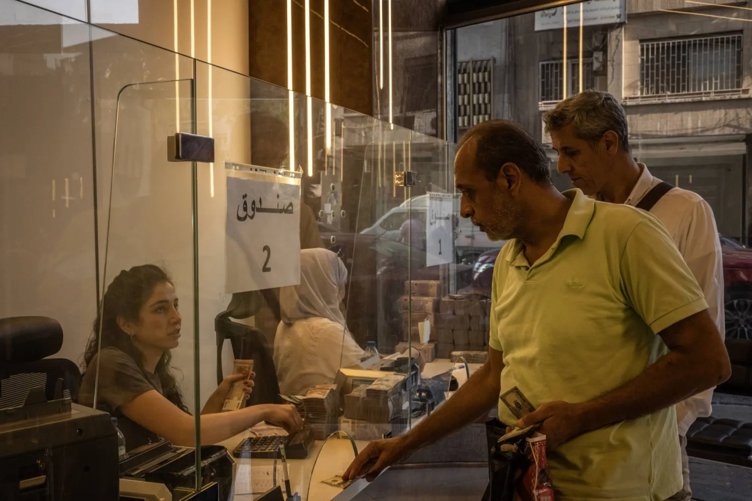 سيدة سورية تعمل بمحل صرافة في دمشق (غيتي)