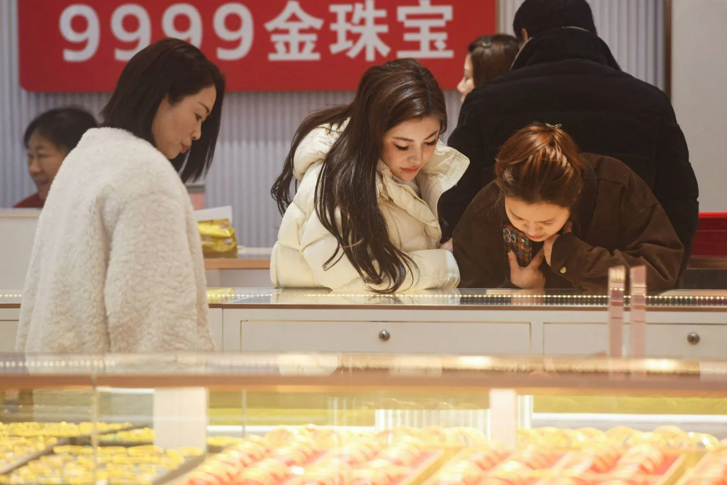 زبائن يتأملون مجوهرات الذهب في متجر للذهب بمدينة هانغتشو، شرق الصين (أ.ف.ب)