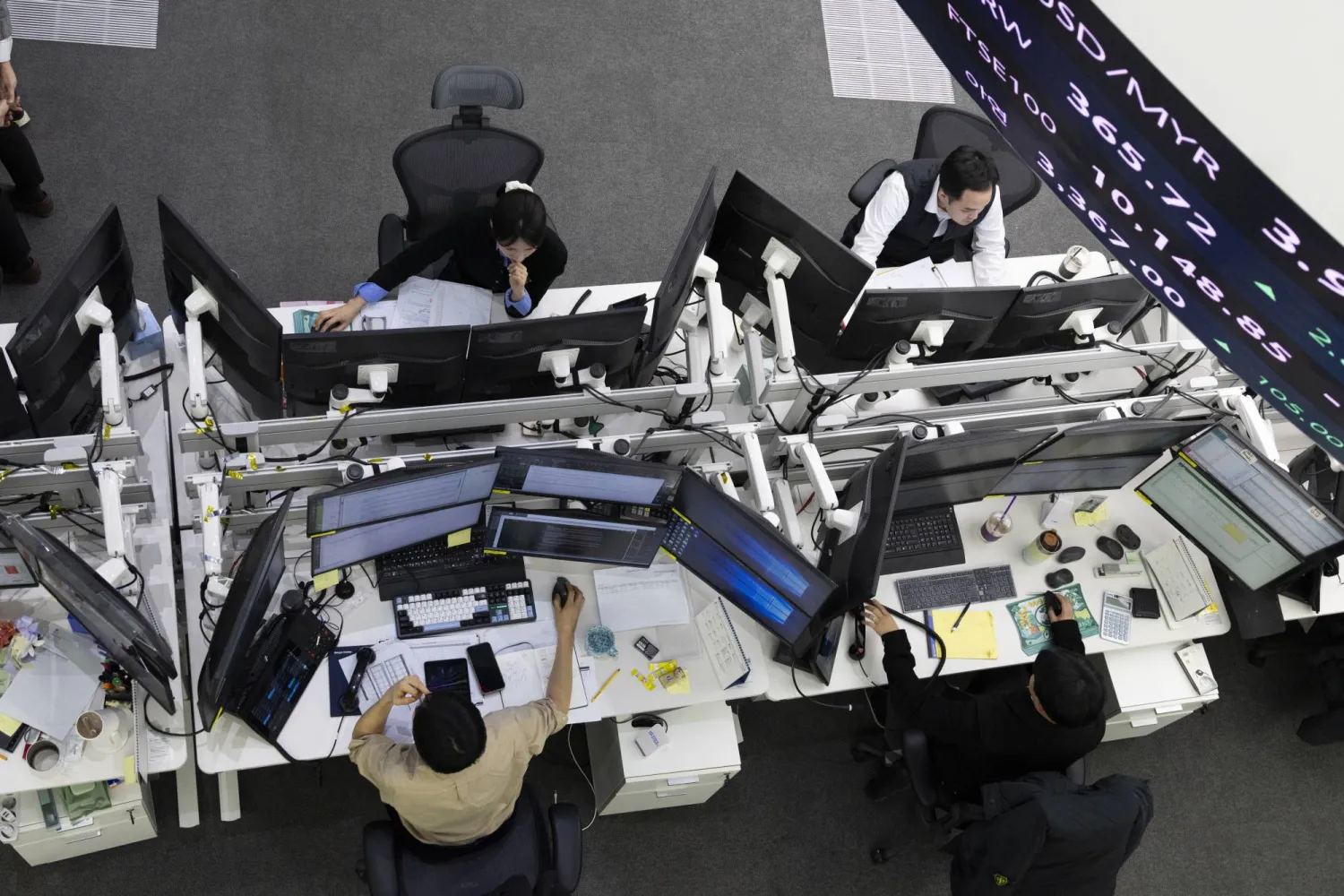متعاملون كوريون جنوبيون يعملون أمام شاشات التداول في بنك هانا في سيول (إ.ب.أ)