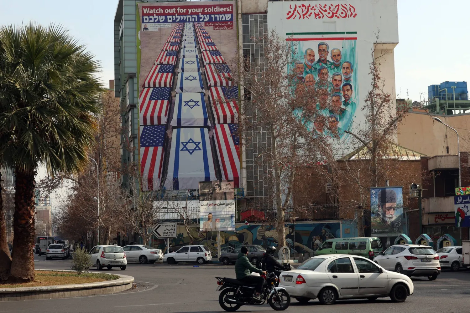 لوحة دعائية مناهضة للولايات المتحدة وإسرائيل على مبنى التنسيق الإيراني - الفلسطيني وسط طهران (إ.ب.أ)