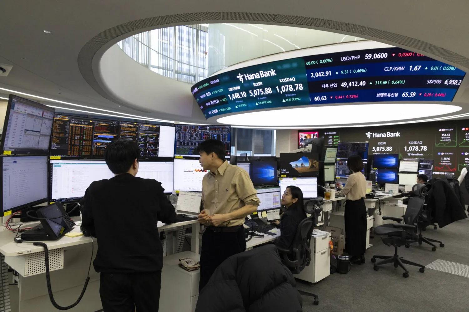 متداولون كوريون جنوبيون يعملون أمام شاشات في بنك هانا في سيول (إ.ب.أ)
