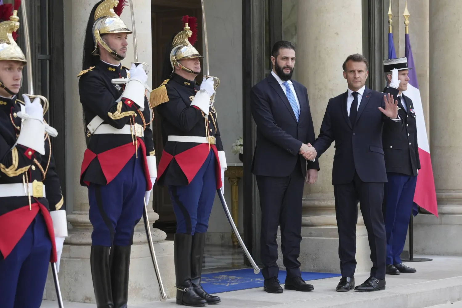 الرئيس الفرنسي إيمانويل ماكرون مستقبلاً الرئيس السوري أحمد الشرع على مدخل قصر الإليزيه في باريس مايو 2025 (أ.ب)