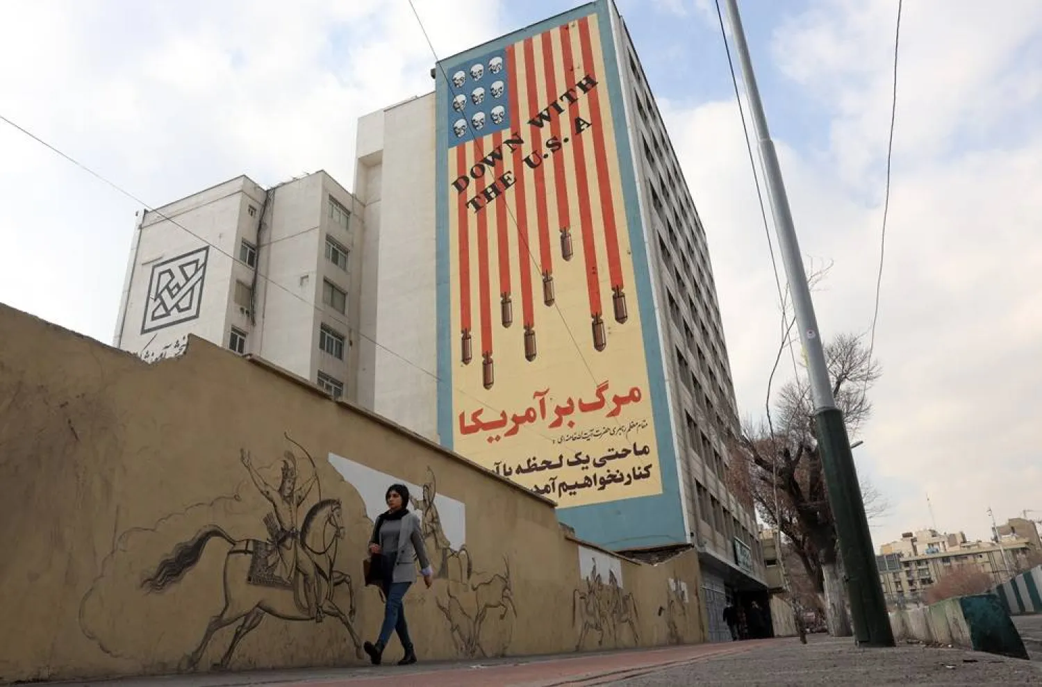 An Iranian woman walks next to an anti-US mural in Tehran, Iran, 29 January 2026. (EPA)