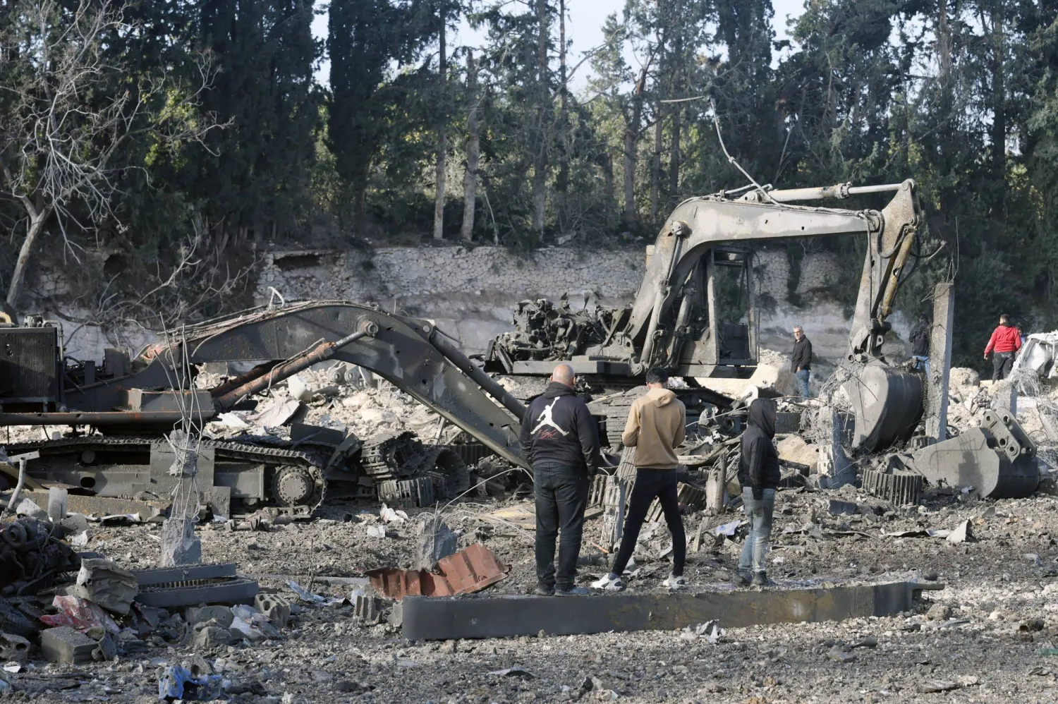 سكان يعاينون آليات لإعادة الإعمار متضررة جراء غارات إسرائيلية استهدفت معرضاً لها في منطقة الداوودية بجنوب لبنان (إ.ب.أ)