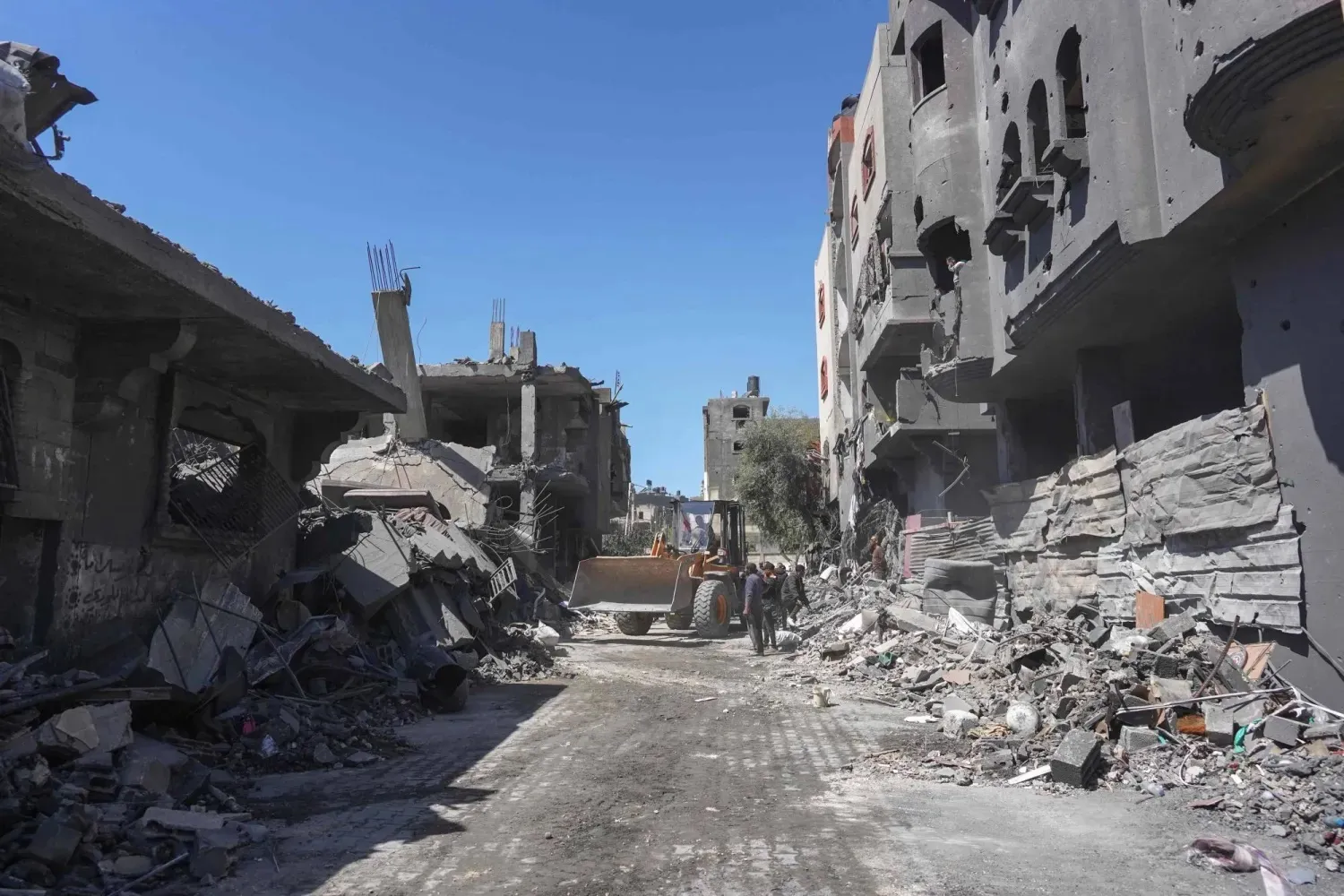 Palestinians clear a road from building rubble with a bulldozer following overnight Israeli bombardment which hit the al-Habash family home at the Nuseirat refugee camp in the central Gaza Strip on March 20, 2024. (Photo by AFP)
