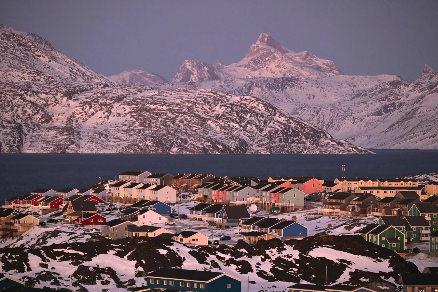 A photo shows a residential area near the airport at the city of Nuuk, western Greenland, with a slightly snow covered mountain in the background, on January 28, 2026. (AFP) 
