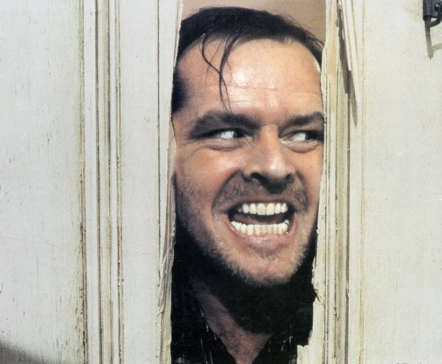 لقطة من الفيلم تحوّلت إلى أيقونة في سينما الرعب يُخرج فيها الممثل جاك نيكلسون رأسه من الباب المكسور (المصدر: IMDb)