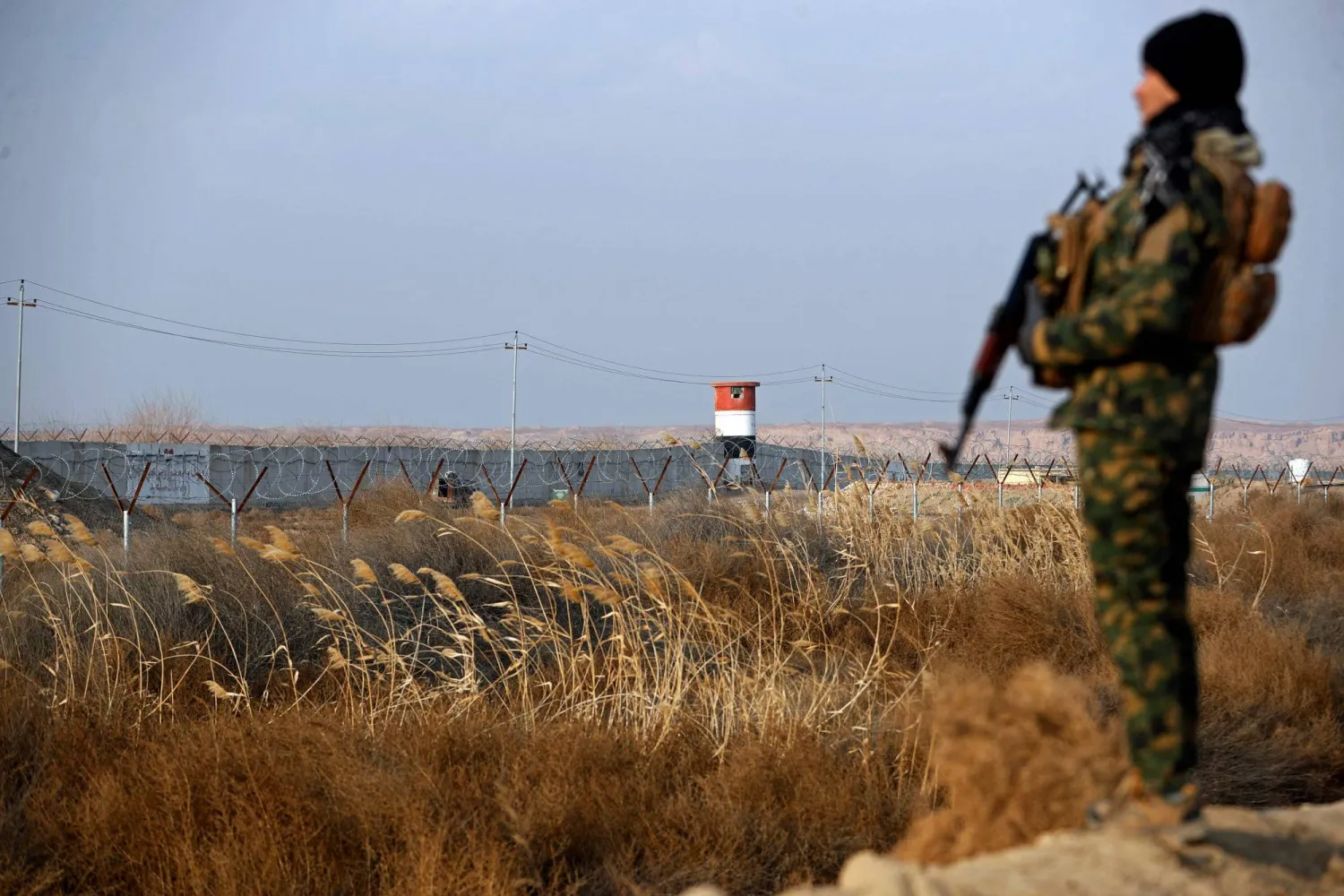 A member of the Popular Mobilization Forces stands guard near a concrete wall at the Iraqi-Syrian border in Al-Qaim, west of Iraq on January 23, 2026. (AFP)