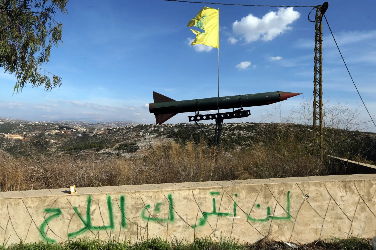 مجسّم لصاروخ رفعه «حزب الله» بمنطقة قلاويه في جنوب لبنان فوق شعار «لن نترك السلاح» (أرشيفية - إ.ب.أ)