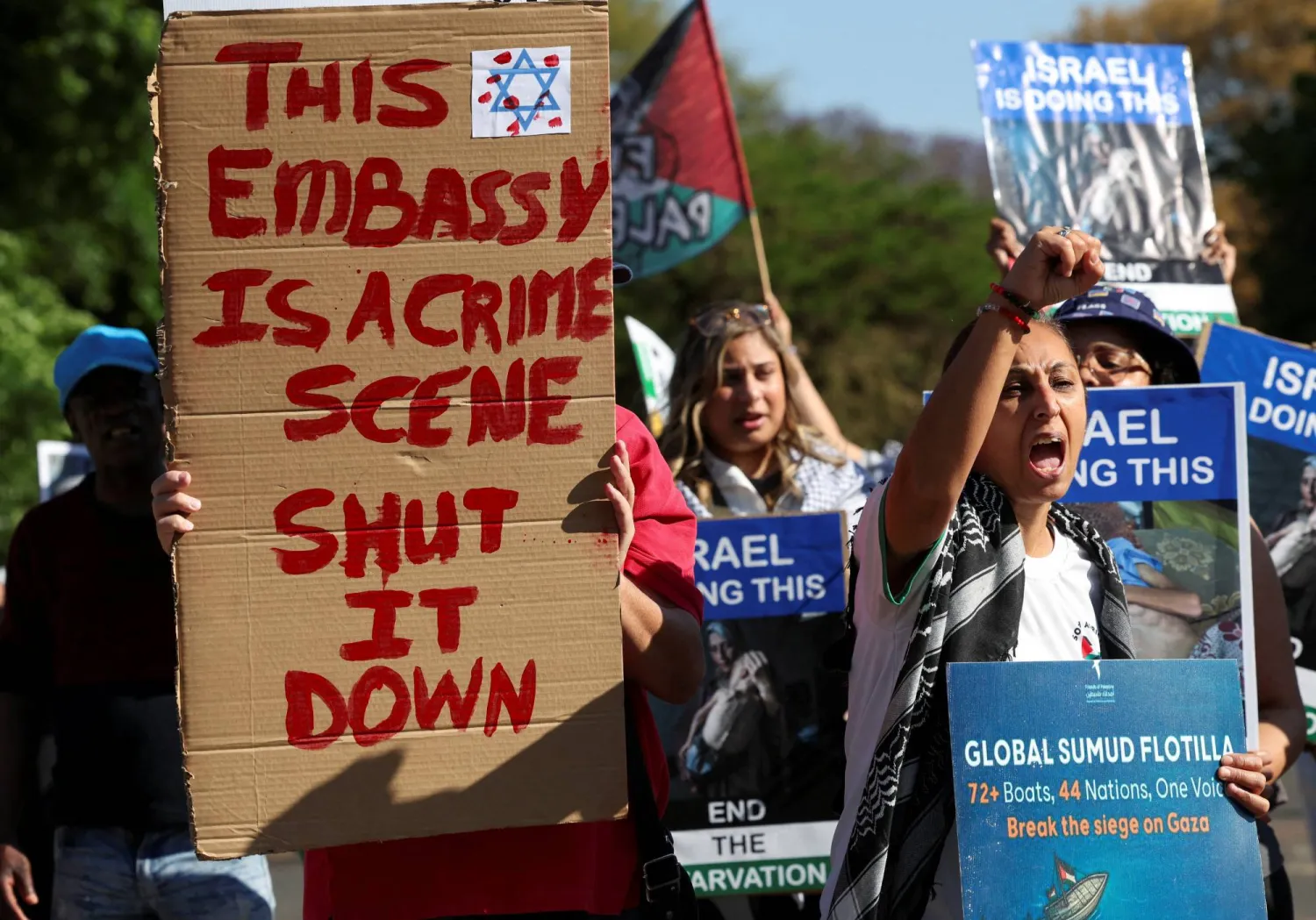 Activists hold placards and shout slogans outside Israel's embassy as they protest the detention of members of a Gaza-bound aid flotilla, in Pretoria, South Africa, October 3, 2025. (Reuters)