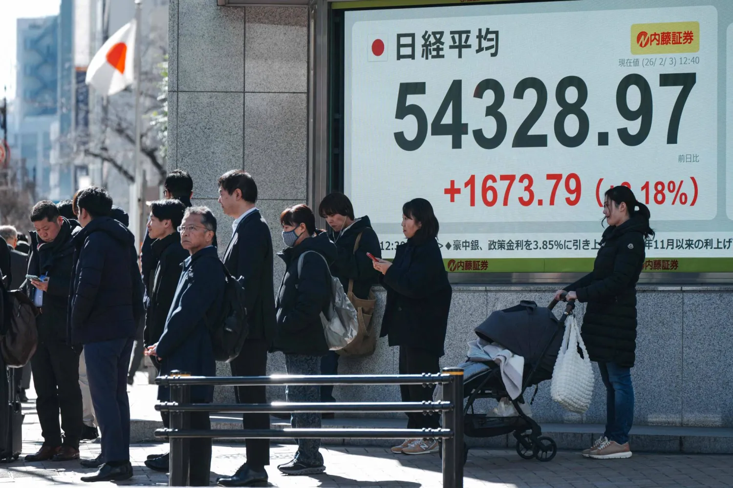 مشاة يمرون بالقرب من شاشة تعرض حركة الأسهم في وسط العاصمة اليابانية طوكيو (أ.ف.ب)