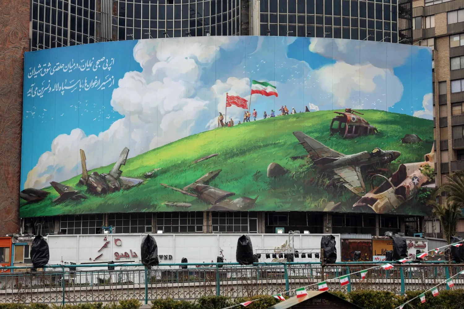 لافتة دعائية معادية للولايات المتحدة معلقة في ميدان ولي عصر وسط طهران اليوم (أ.ف.ب)