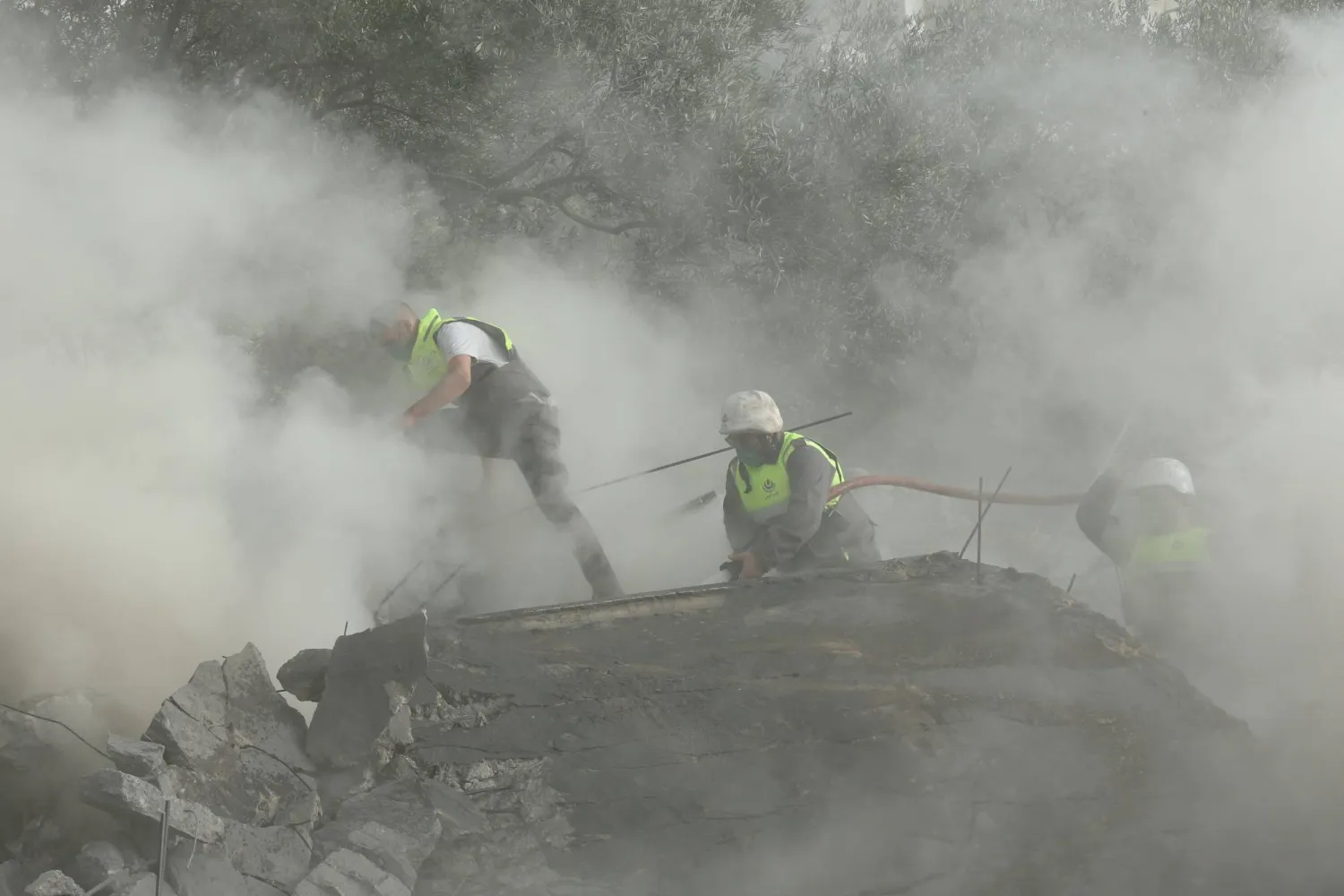 عناصر الدفاع المدني يكافحون النيران في موقع غارة جوية إسرائيلية استهدفت مبنى في قرية عين قانا جنوب لبنان (أ.ف.ب) 
