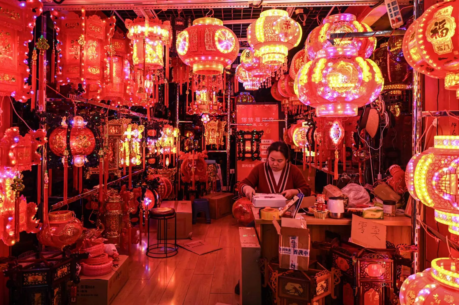 بائع ينتظر الزبائن في كشك لبيع الفوانيس قبل حلول السنة القمرية الجديدة للحصان (أ.ف.ب)