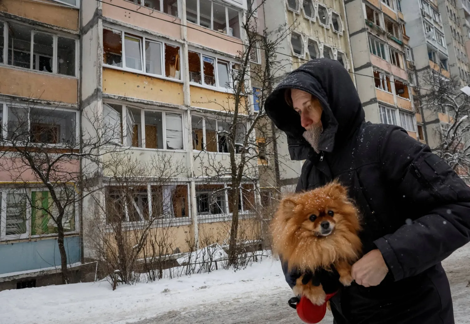 A resident with a dog walks near an apartment building damaged during a Russian overnight drone strike, amid Russia's attack on Ukraine, in Kyiv, Ukraine February 5, 2026. REUTERS/Gleb Garanich 