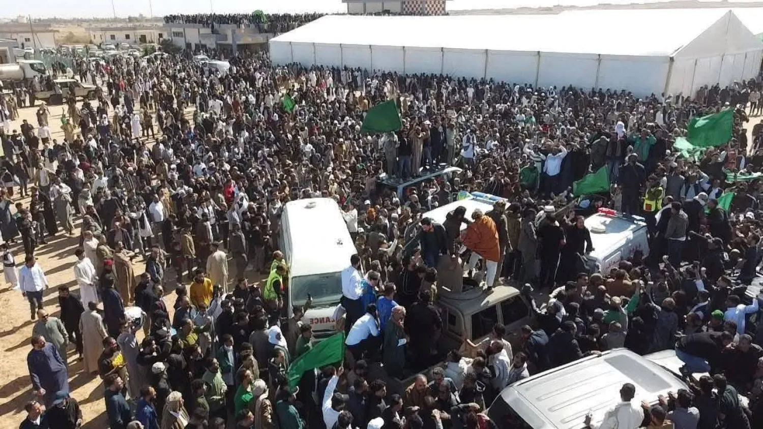 جموع من المشيّعين يطوّقون سيارة الإسعاف التي تحمل جثمان سيف القذافي في مطار بني وليد (صفحات مؤيدة لسيف)